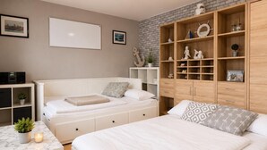 A bedroom with a bed, a desk, a wardrobe, and a brick wall.