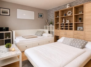 Ein Schlafzimmer mit Bett, Schreibtisch, Kleiderschrank und einer Ziegelwand.