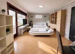 A modern bedroom with two beds, a desk, and a TV.