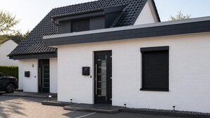 A modern two-story building with a white exterior, black doors, and a tiled roof.