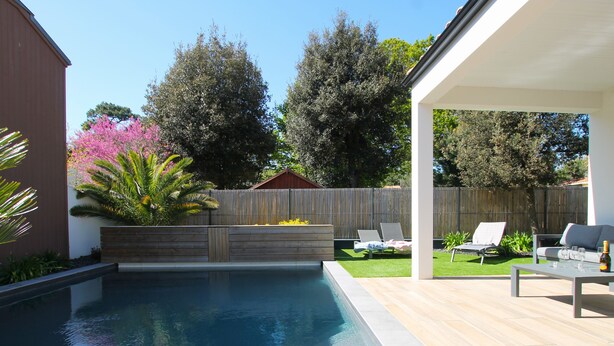 A backyard with a swimming pool, a wooden deck, and a covered patio area. - Villa Agapanthes, perfect in any season, with heated swimming pool (Saint-Vincent-sur-Jard)