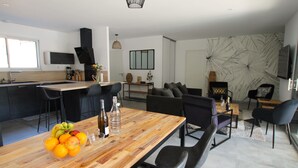 A modern kitchen with a wooden island, bar stools, and a dining table with chairs. - Villa Agapanthes, perfect in any season, with heated swimming pool (Saint-Vincent-sur-Jard)