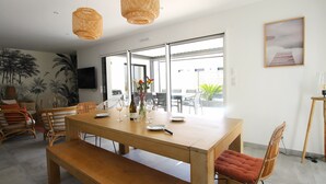 Een moderne eethoek met een houten tafel, rieten stoelen en een bank.