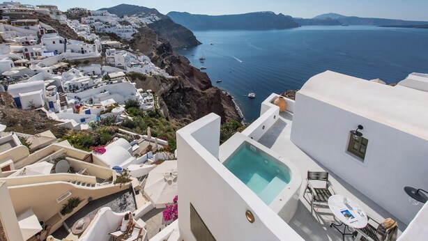 A coastal town with white buildings, a swimming pool, and a view of the sea. - Rhenia Suites-Prive Jacuzzi&Caldera View (Santorini)