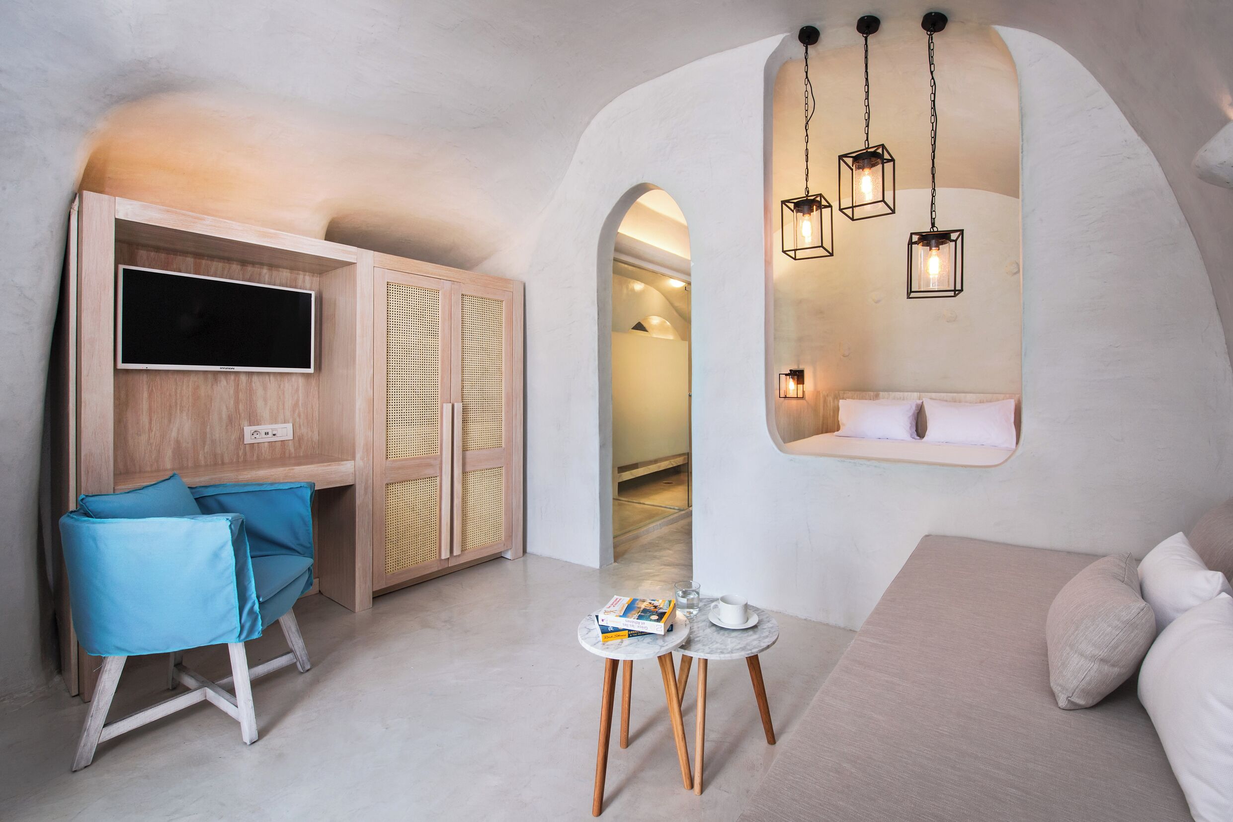 A modern room with a TV, seating, and a unique arched window.