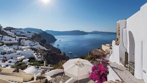 A coastal village with white-washed buildings, a clear blue sea, and boats anchored nearby. - Rhenia Suites-Prive Jacuzzi&Caldera View (Santorini)