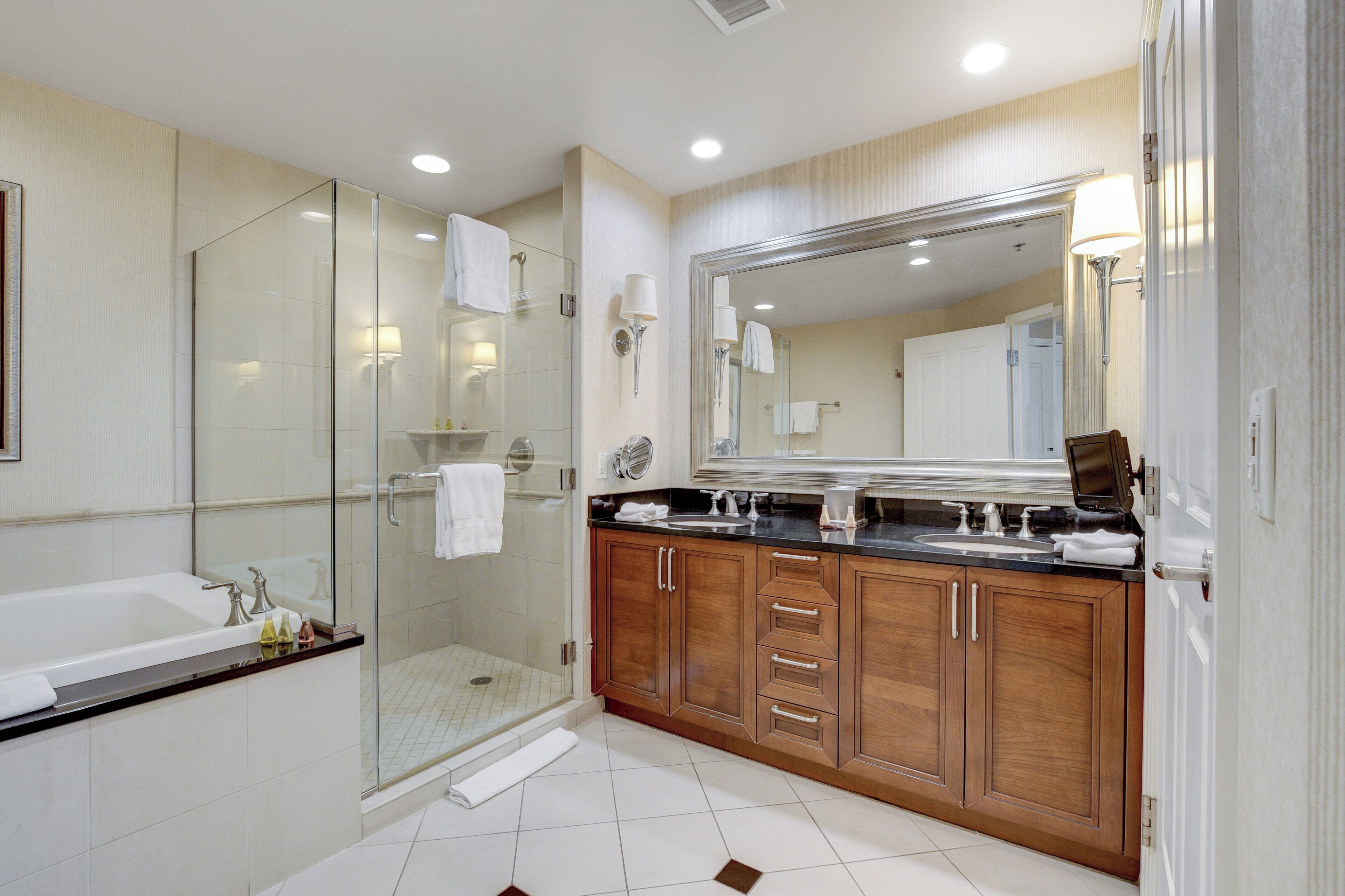A modern bathroom with a glass-enclosed shower, a large mirror, and wooden cabinets.