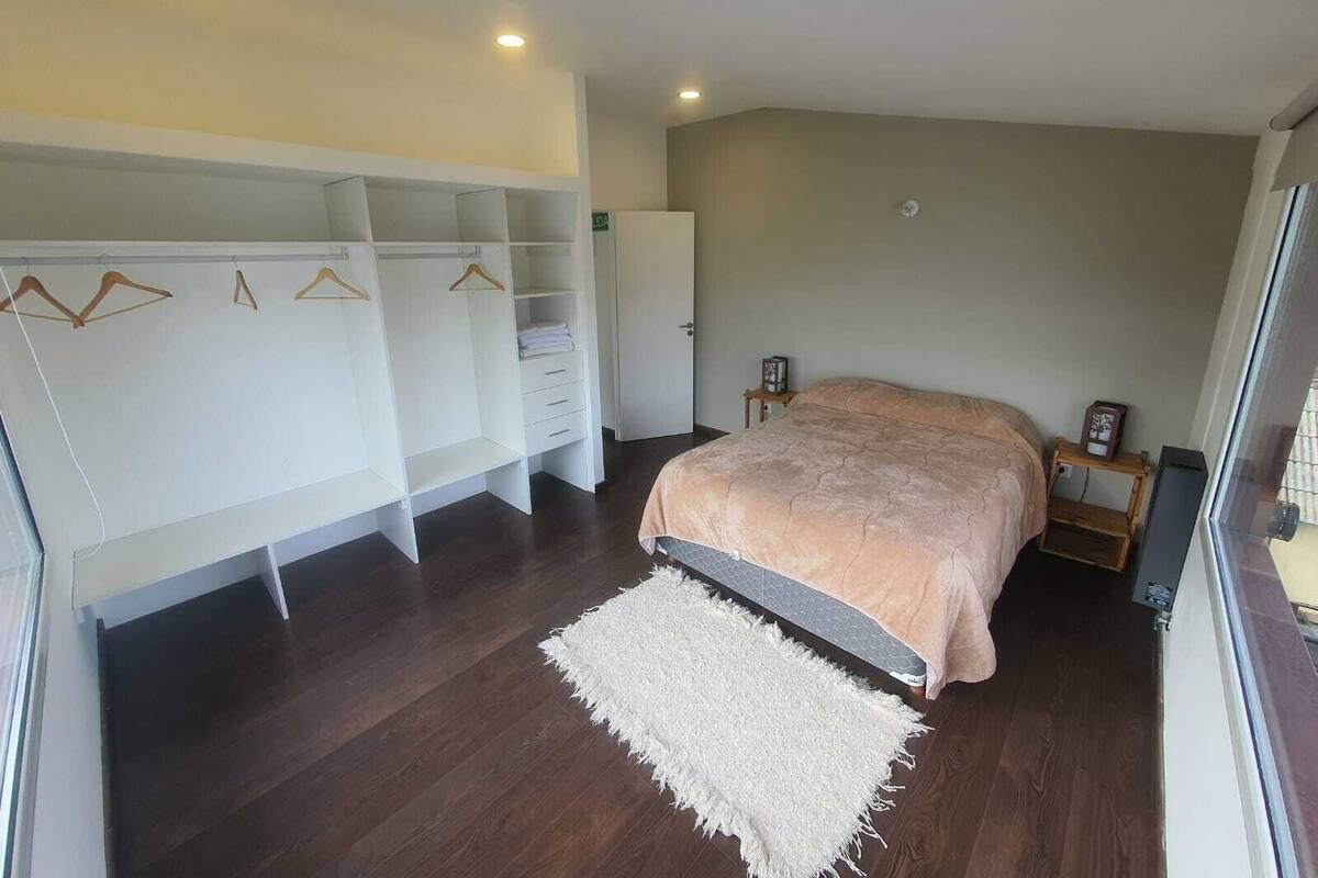 Quarto com cama, closet espaçoso e tapete branco.