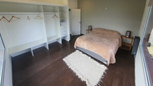 Quarto com cama, closet espaçoso e tapete branco.