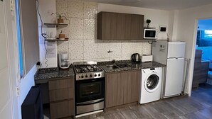Cozinha compacta com fogão a gás, forno, máquina de lavar e micro-ondas.