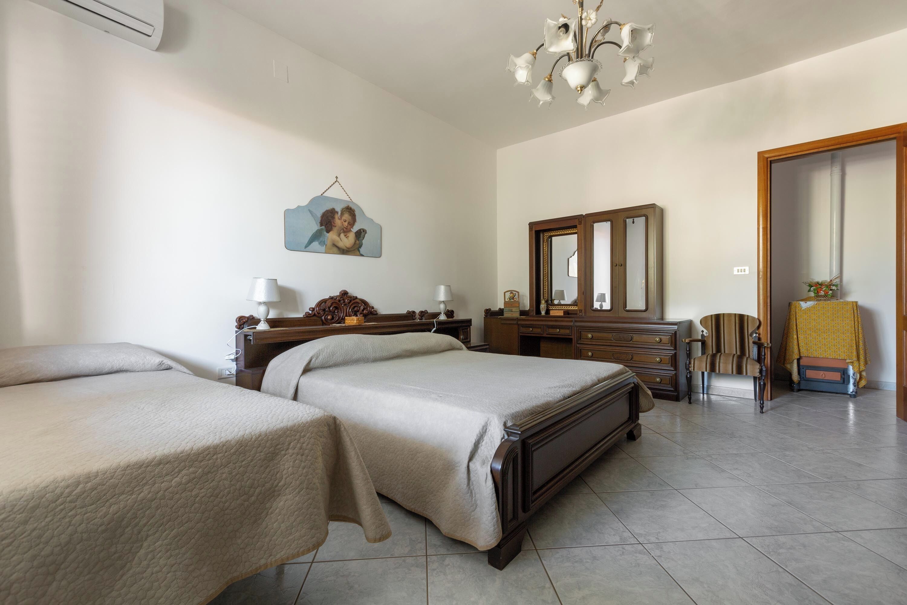 A hotel room with two beds, a wooden dresser, a mirror, a chair, and a hanging picture.