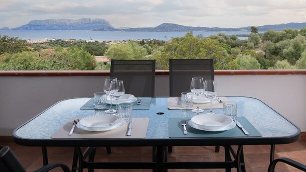 Une table dressée pour deux personnes, avec vue sur la mer et les montagnes.