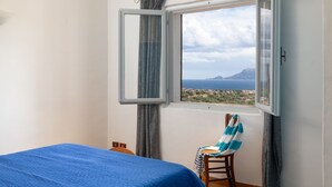 Une chambre à coucher avec un lit, une chaise, une fenêtre avec des rideaux et une vue sur un paysage.