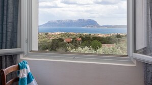 Une pièce avec vue sur un paysage montagneux et un plan d’eau.