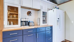 A modern kitchen with white cabinets, a blue countertop, and a white refrigerator.