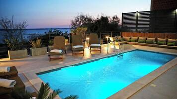 Relax by the pool surrounded by lush greenery and a stunning sea view.