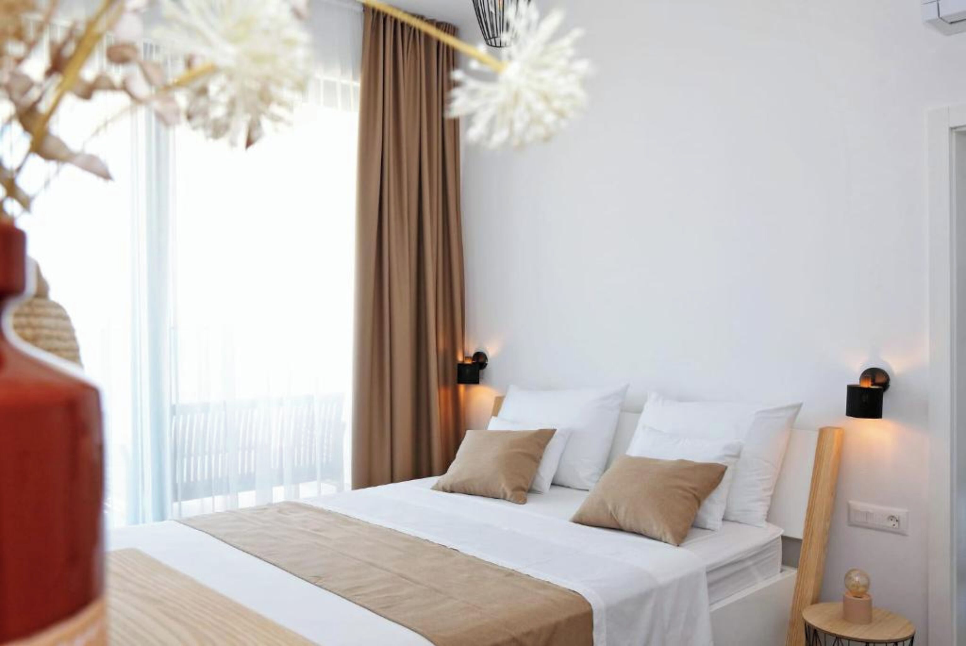 A neatly arranged hotel room with a bed, two bedside tables, and a window with curtains.