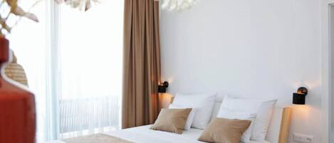 A neatly arranged hotel room with a bed, two bedside tables, and a window with curtains.