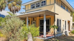 A two-story house with a covered porch and a small garden area. - Enjoy the quiet and walk to downtown! (Cedar Key)