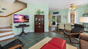 A living room with a TV, bookshelf, and seating area. - Enjoy the quiet and walk to downtown! (Cedar Key)