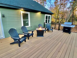Une terrasse avec des fauteuils Adirondack, un foyer et un barbecue.