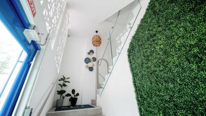 A staircase with a glass railing, a potted plant, and a wall with a green wall covering.