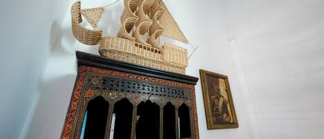 A decorative ship model on a shelf, a framed painting on the wall, and a potted plant in the corner.