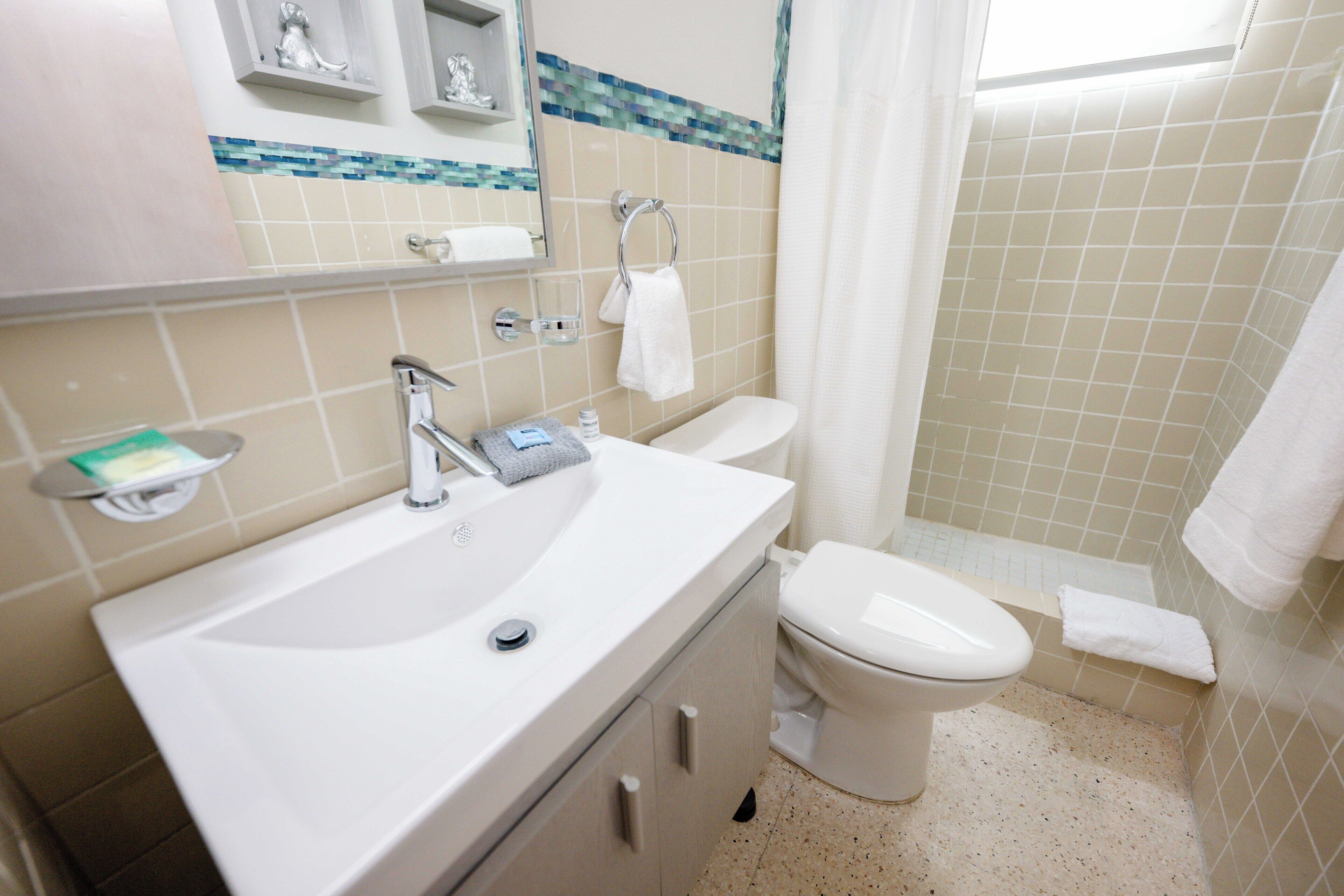 Une salle de bain avec un lavabo, un miroir et des toilettes.