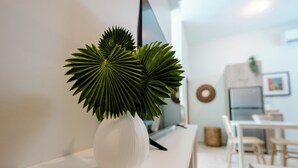A white vase with two green plants on a white console table in a modern living room. - Chic 1 Bedroom Studio | Rooftop Pool + Parking (San Juan)