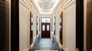 Un couloir orné de moulures décoratives, doté d’un sol à motifs et terminé par une porte.