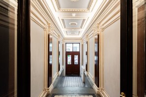 A hallway with ornate moldings, a patterned floor, and a door at the end.