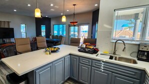 A modern kitchen with a central island, grey cabinets, and a dining area with wicker chairs. - Beautiful House (Las Conchas)