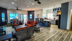 A spacious living area with a dining table, sofas, and a kitchen area with cabinets and a refrigerator. - Beautiful House (Las Conchas)