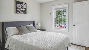 A bedroom with a bed, a ceiling fan, a window with a view, and a door. - 2 Bedroom Beacon Cottage 3 - Two bedrooms, one sleeper sofa and a kitchenette (Allons)