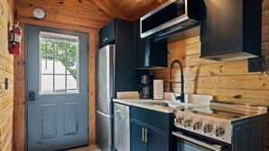 Eine kleine Küche mit Kühlschrank, Herd, Mikrowelle und Kaffeemaschine.