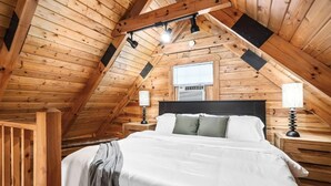 A wooden-paneled attic bedroom with a bed, nightstands, and a window. - Eagle's Perch Cabin 13 with Loft - One bed in loft, sleeper sofa and full kitchen (Allons)