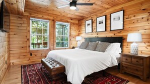 A wooden-paneled bedroom with a bed, bench, bedside tables, and framed pictures on the wall. - 10 Person Golden Cedar Lodge 16 - 2 Floors and a 3rd floor loft, entertainment room, full kitchen (Allons)