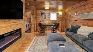 A cozy cabin interior with a wooden interior, a dining area with a table and chairs, a sofa, and a television. - 10 Person Golden Cedar Lodge 16 - 2 Floors and a 3rd floor loft, entertainment room, full kitchen (Allons)