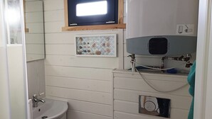 Un baño con lavamanos, espejo y televisor sobre el lavamanos.