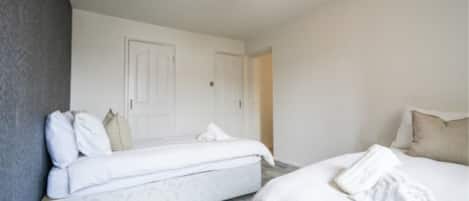 A bedroom with two beds, a white door, and a light fixture.