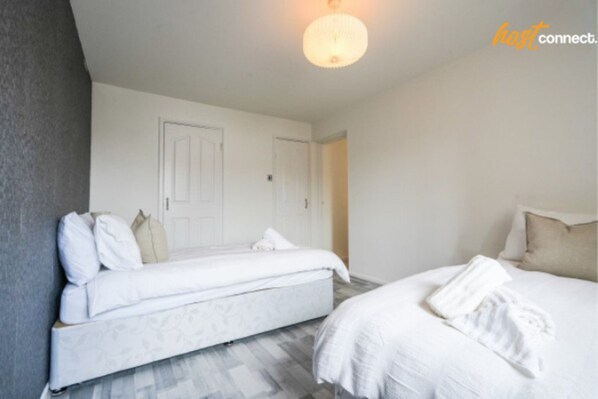 A bedroom with two beds, a white door, and a light fixture. - Livingston 4 Bed + Car Space (West Lothian)
