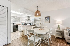 A modern kitchen with white cabinetry, a central island, and a hanging wicker light fixture.