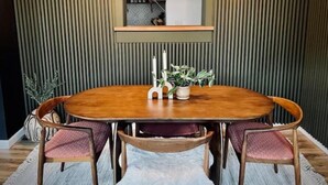 A dining area with a round wooden table, four chairs, a potted plant, and a mirror above the table. - The 'Posh Pickle'- Chic & Unique

 (louisville)
