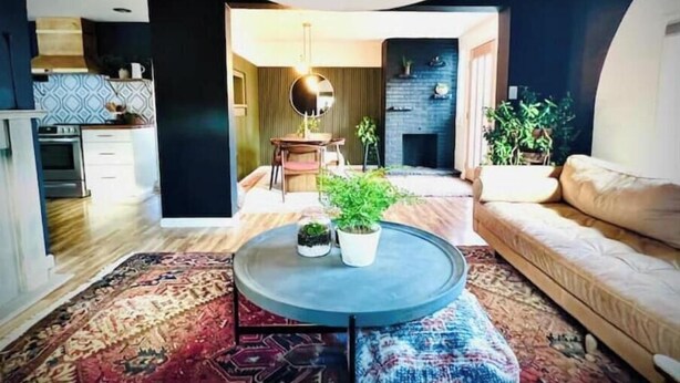A modern living room with a round coffee table, a sofa, a fireplace, and a kitchen in the background. - The 'Posh Pickle'- Chic & Unique

 (louisville)