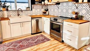 A modern kitchen with white cabinets, a stainless steel oven, and a wooden countertop. - The 'Posh Pickle'- Chic & Unique

 (louisville)