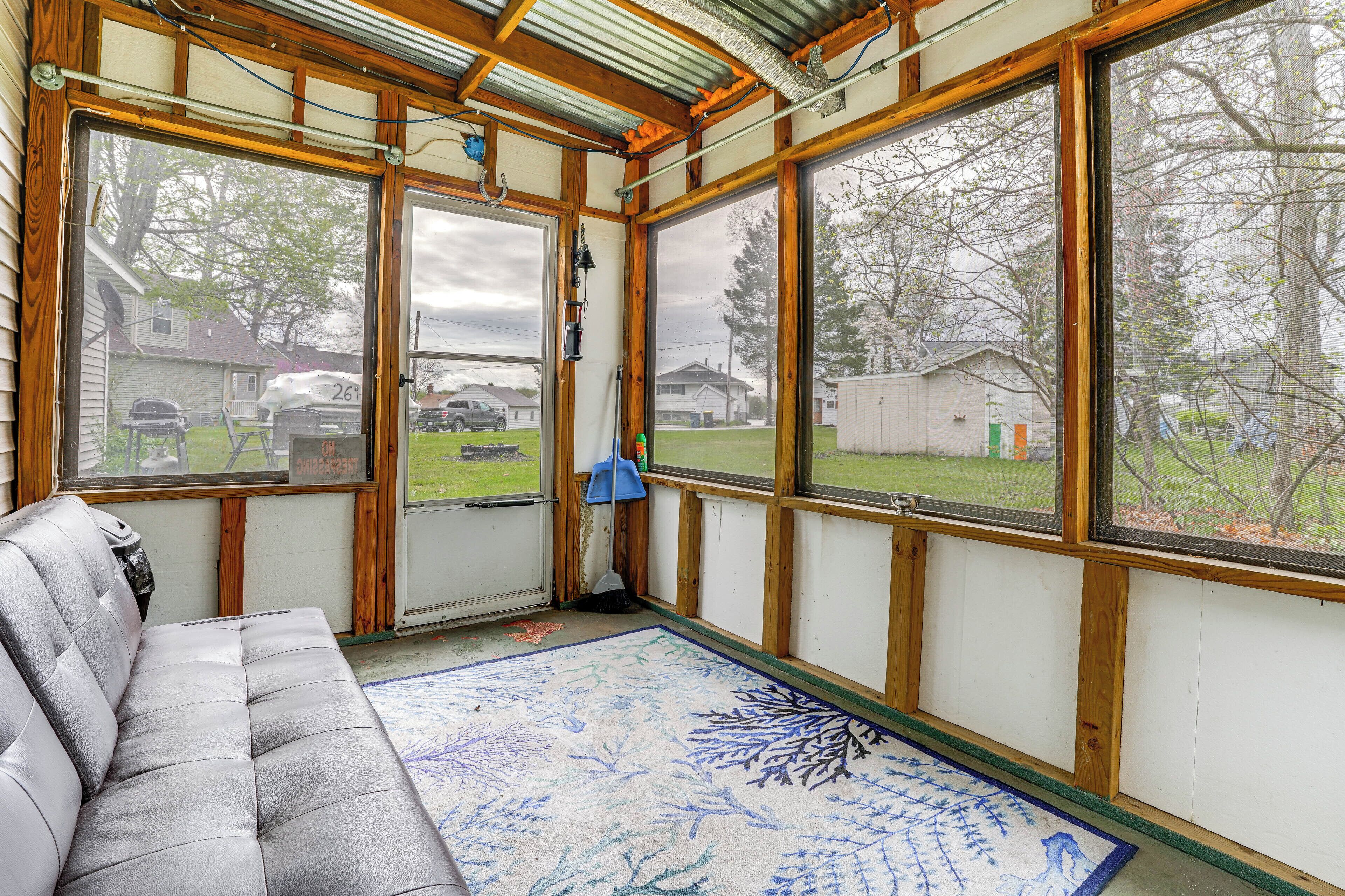 Ein Zimmer mit grauem Sofa, großen Fenstern und Blick auf einen Garten.