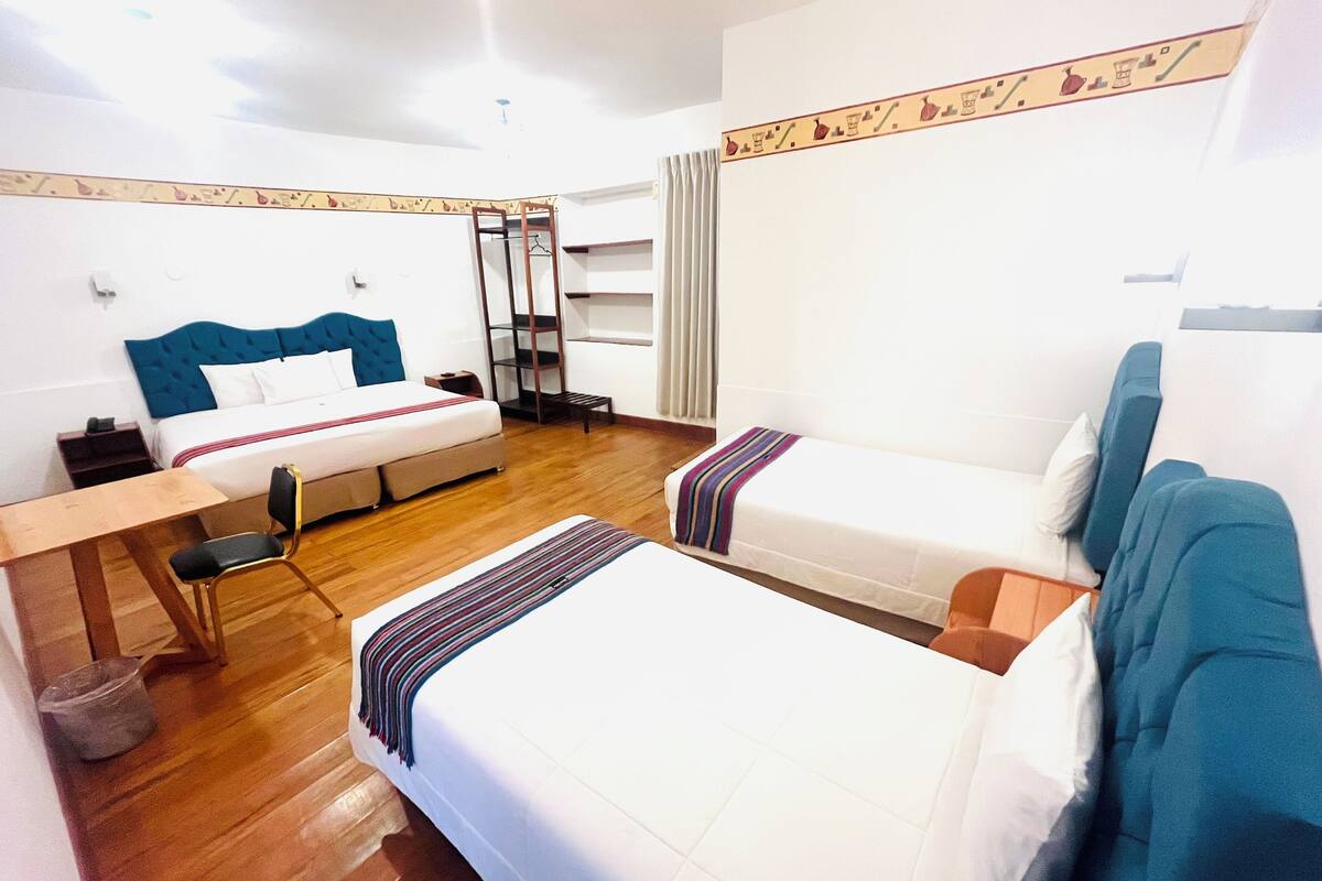 Une chambre d’hôtel avec deux lits, un bureau, une chaise, une armoire et un radiateur.