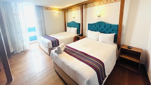 Une chambre d’hôtel avec deux lits, un plancher en bois, une couverture à rayures et une petite table d’appoint en bois.