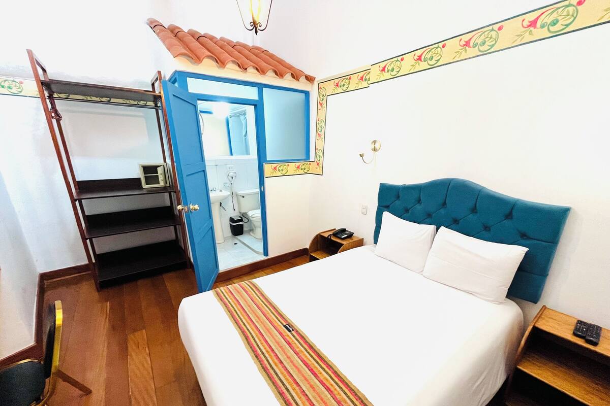 Une chambre d’hôtel comprenant un lit, une armoire, une salle de bain et une table de chevet.