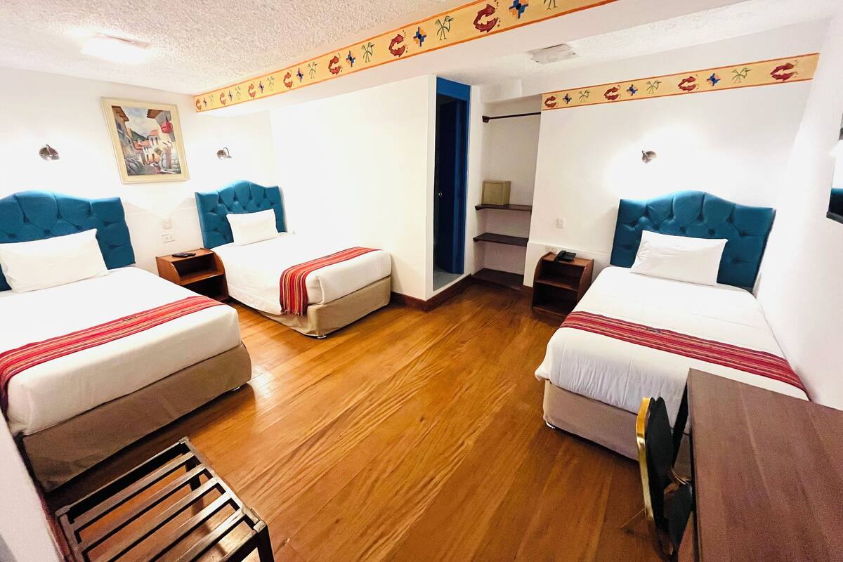 Une chambre d’hôtel avec deux lits, un plancher en bois, un tableau au mur et une bordure décorative.